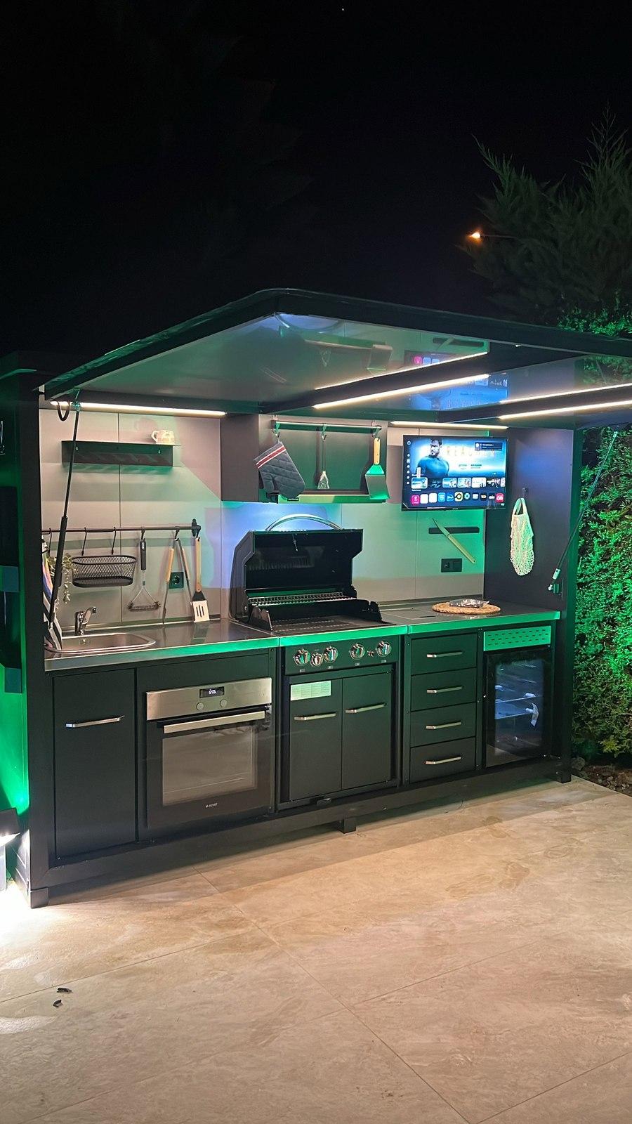 Opengeklapte buitenkeuken met sfeervolle LED-verlichting in de avond
