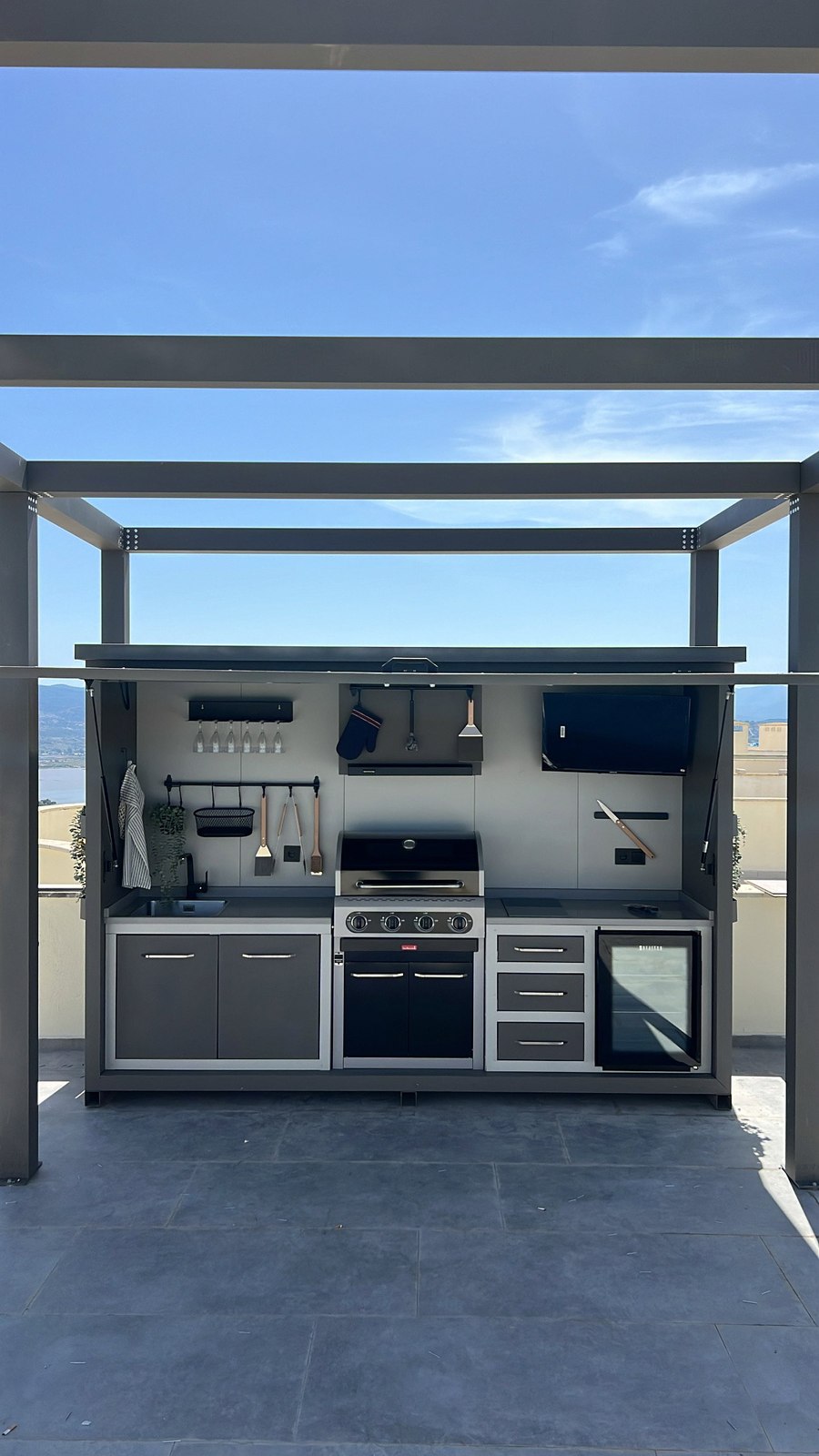 Opengeklapte buitenkeuken onder een pergola op een dakterras